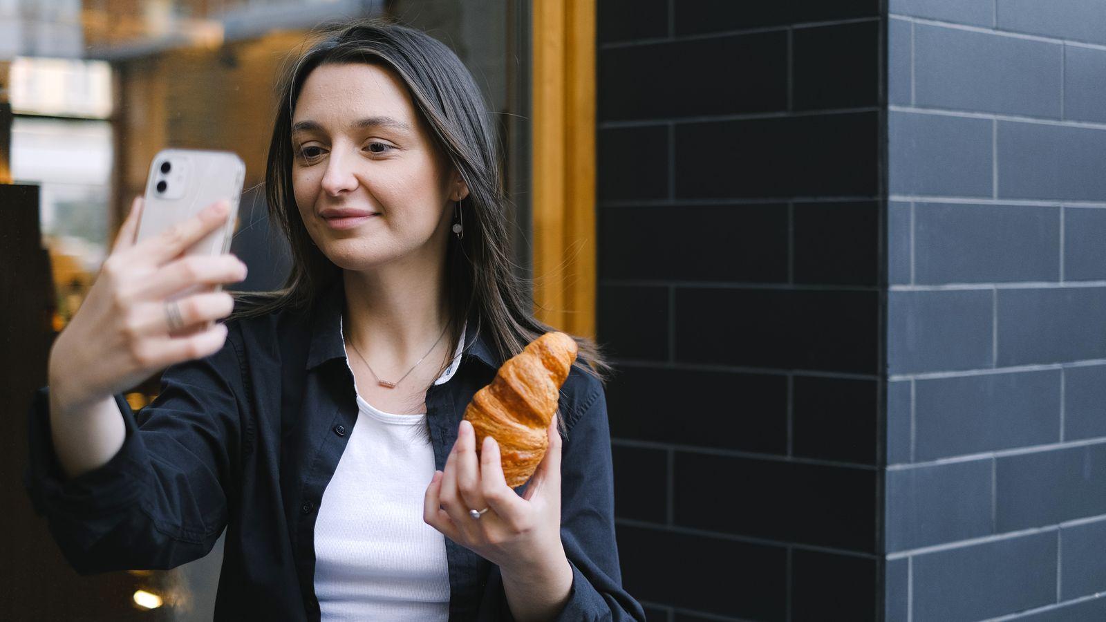 A croissant, a phone, and a creator mid-selfie