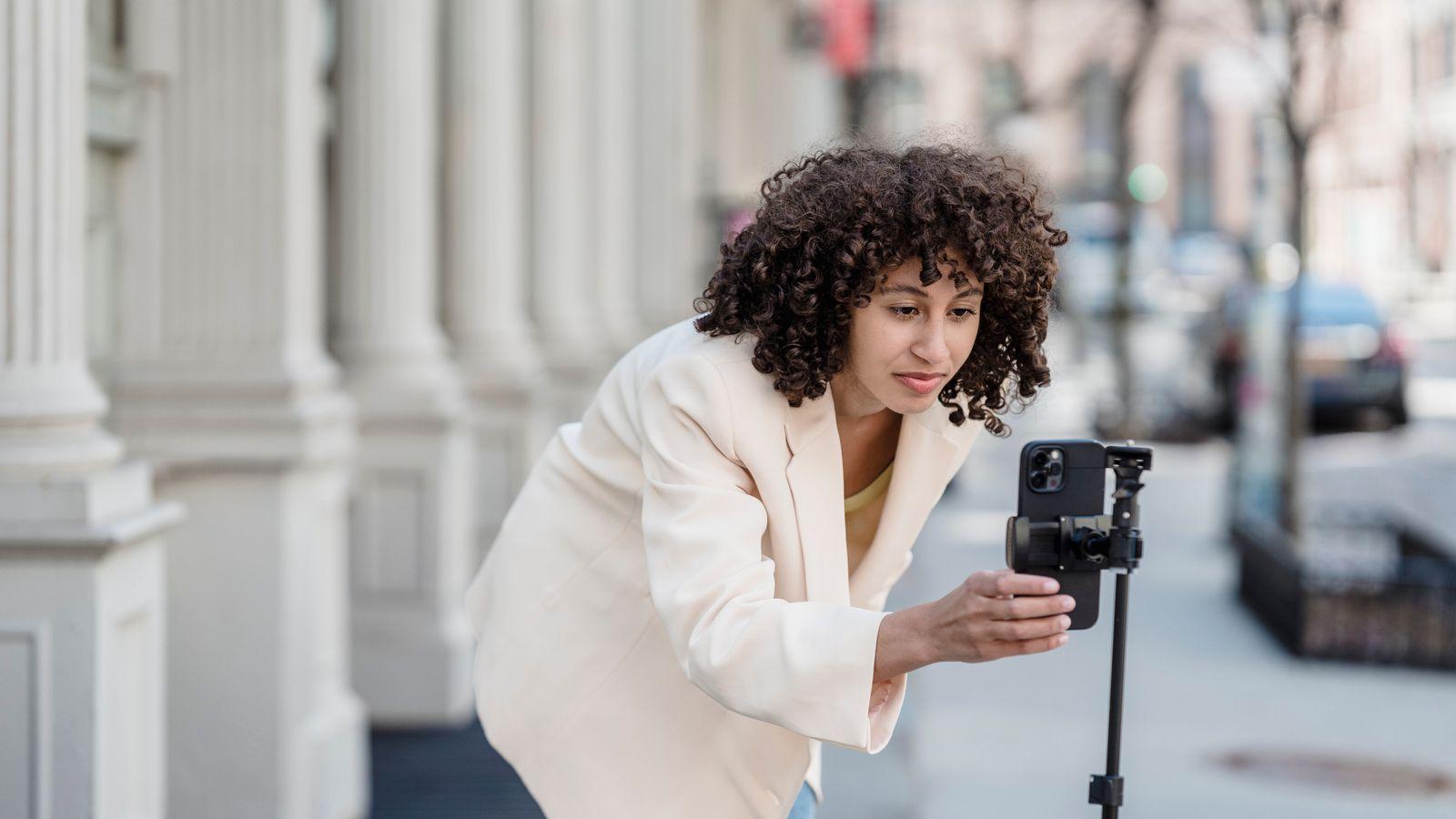 A creator leaning into her phone on a tripod, framing the next video